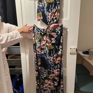 Långklänning med cut out  - Blomning långklänning med öppet i minjan. Bra skick!