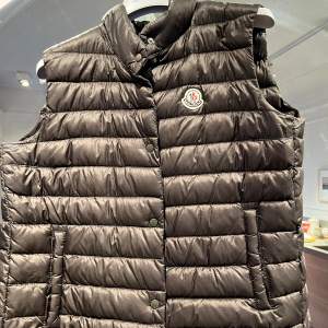 Olive grön med slit detalj bak och 2 fickor med knapp fram.  Finns fler bilder om man googlar moncler shoko vest 