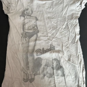 Vit Blondie Tröja - Säljer denna snygga, vita Blondie tröjan som inte har använts på ett bra tag då den har legat längst bak i garderoben. Det står att dess storlek är S, men skulle vilja säga att passformen är mer en M.