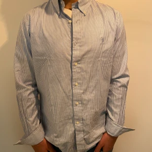 Ralph Lauren skjorta - Fräsch skjorta som är perfekt till sommaren. Den är helt felfri och inte använda. Nypris på denna är ca 1700kr.  Storlek L men sitter som M. Har du frågor så är det bara att skriva.