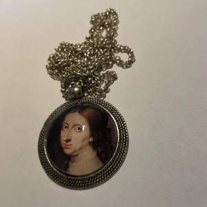 Halsband i silver med berlock. Motivet är en gammal målning på drottning Kristina. Finns inget spänne men så man får dra halsbandet över huvudet.