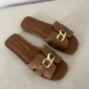 Bruna tofflor med guld detaljer  - Stl 38  Nyskick använd en gång 