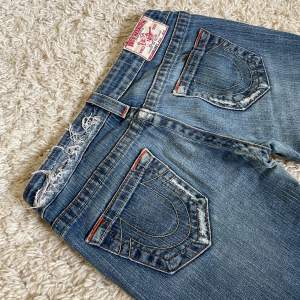 True Religion jeans med snygga slitningar och detaljer i perfekt skick.  Lågmidjad och bootcut modell. ❤️ Innerben: 85cm, midja rakt över: 37cm. Jag är 167. Meddela om fler mått önskas! 🫶 Håll koll på min profil, säljer mestadels vintage jeans. 😍