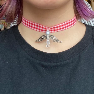 Röd och vitrutig choker - En röd och vitrutig choker med en lyckoångel på! ❤️