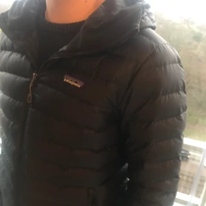 Patagonia Dunjacka Svart Storlek S - En svart dunjacka från Patagonia i storlek S som tyvärr har blivit för liten på mig. Min bror på bilderna är 184cm och väger 67kg. Jackan är i bra skick och har inga defekter. Kontakta mig för fler bilder eller om ni har andra funderingar!😁