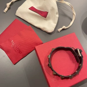 Valentino armband - Säljer mitt jättesnygga svarta valentino armband med guldnitar, väldigt bra skick!💗Dustbag till armbandet, asken, äkthetsbevis och extra nitar till armbandet ingår.🥰Pris kan diskuteras!