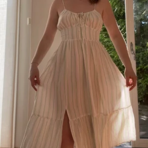 Randig midiklänning - Säljer nu denna fina sommarklänning i viskos/linneblandning. Den har rosa och gröna små ränder och är öppen i ryggen. Använd ca 2-3 gånger. Hör av dig vid frågor! 🥰