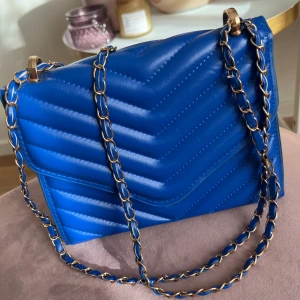 💛 Blå kuvertväska med guldpläterade detaljer 💛 - Märke: Okänt, köpt i andra hand . Längd: 20 cm i botten . Bredd: 16 cm . Material: Okänt . Utan anmärkning men i använt skick.