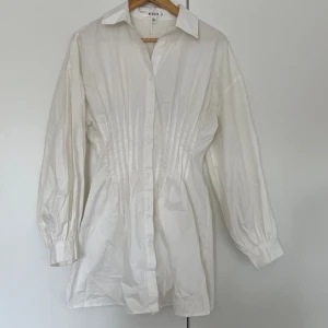 Skjortklänning - Skjortklänning med puffiga armar. Finns någon enstaka ljus fläck (finns fler bilder att få). 