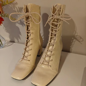 Högklackade beiga boots  - Högklackade beiga boots med snörning Väldigt fint skick, köpa secondhand men aldrig använda efter det.