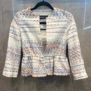 Kofta - Fin vit kofta från zara med färgglada och glittriga detaljer. Volang nertill på koftan samt ett spänne i mitten så man kan ha den både öppen och stängd. Trekvartsärm med slits. Storlek xs, liten i storleken. 