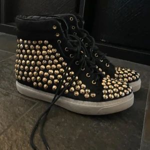 Svarta mockaskor med gulda nitar - Ett par supercoola höga sneakers tillverkade av premiummocka och läder, med snygga guldignitar som detalj🖤