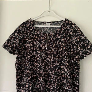 Blommig T-shirt blus - Svart t-shirt med rosa Blom detaljer. Passar perfekt nu till sommarn!💕 Är i storlek 146/152 men skulle nog passa dig med xxs/xs.🌸