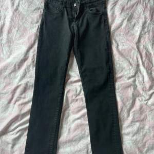 Ett par svarta skinny jeans i storlek 152. Byxorna har en klassisk femficksdesign och är tillverkade i denim. De har en knapp- och dragkedjestängning framtill.