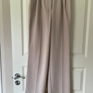 Ljusa kostymbyxor NA-KD - Ljusrosa/beiga kostymbyxor från NA-KD i storlek 34. Något vidare byxben i modellen. Använda enstaka gånger. 