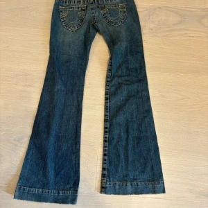 Utsvängda true religion jeans - Säljer dessa supersnygga lågmidjade bootcut jeansen från true religion som är i ett skönt material och har bra passform