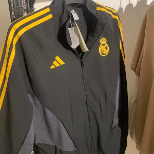 Real Madrid zip tröja - En väldigt fin äkta Real Madrid tröja som även är oanvänd. Säljer pga storlek, PRIS KAN DISKUTERAS! 