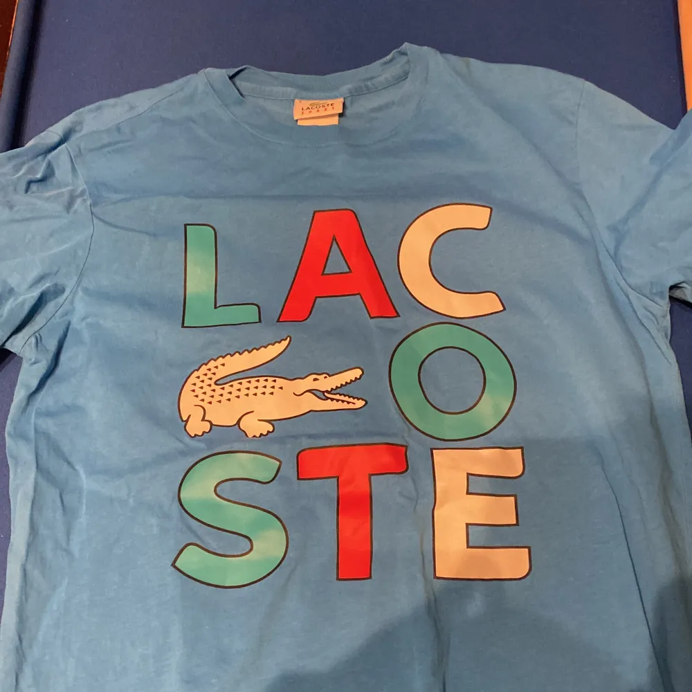 En t shirt av märket Lacoste. Skick 8,5/10, använd med inga defekter. Skulle säga att den passar någon som har storlek S eller möjligtvis M. Säljs billigt för att den ej passar.. T-shirts.