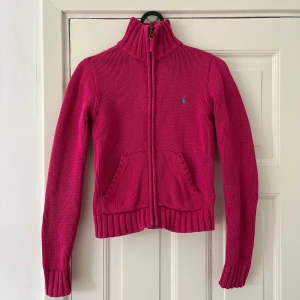 Stickad kofta Ralph Lauren - Rosa/lila kofta från Ralph Lauren i storlek ”XL (16 år)” i barnstorlek, skulle säga att den passar xxs. Använd ett fåtal gånger. Säljs pga för liten för mig.
