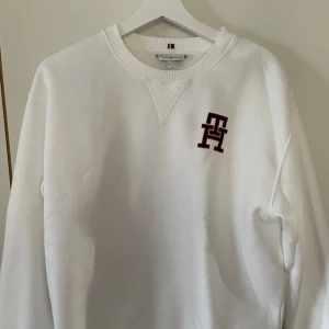 Tommy Hilfiger sweatshirt  - Tommy Hilfiger sweatshirt. Vit med tryck på bröstet. Köpt på NK, bara använd en gång. Den är i storlek M. Köparen står för frakten.