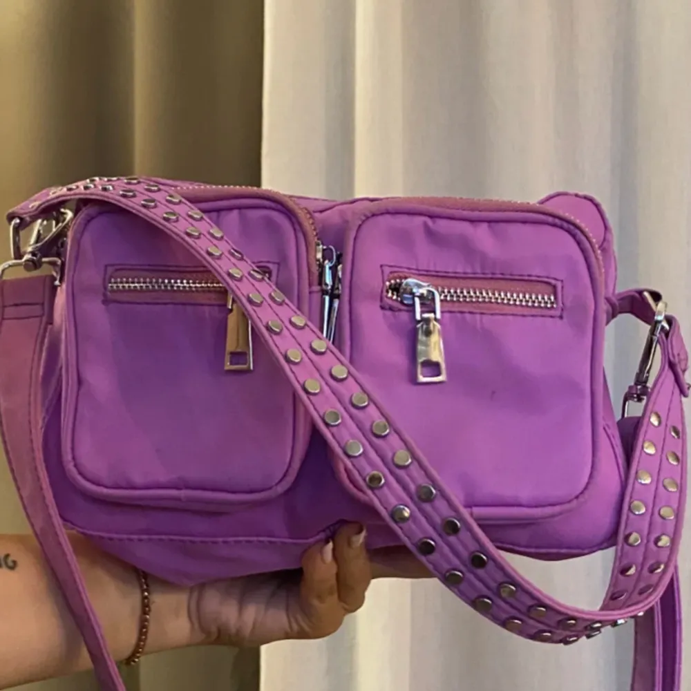 Lila/rosa  väska från noella i vattentåligt material. Det finns både ett lång och ett kort band. 💜💗. Väskor.