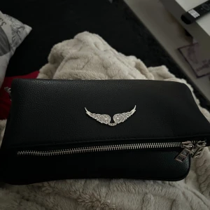 Zadig & Voltaire väska - Fick den på nyår, ser helt oanvänd ut. Finns två band ett kort och ett långt. Den har tre fack och magneten är stark så den öppnas inte. Man får med dust bag. Köptes för 3595kr  vill få den såld fort
