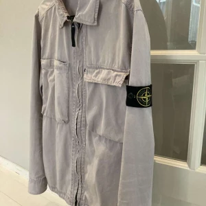 Stone Island Overshirt - Stone Island Overshirt⭐️ Superbra skick och inga defekter finns. Den är grå men har en cool nyans av lila. Skriv vid minsta fundering eller fråga så löser vi!🦈 (Pris kan diskuteras!)