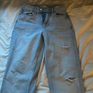 Ljusblåa jeans med ett små par hål(dem ska vara så) och med slits längst ner om benen, jätte snygga med tvärt för små 