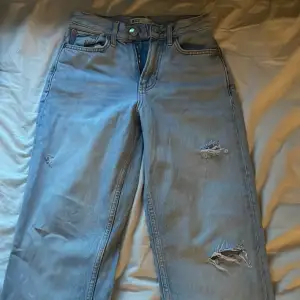 Ljusblåa jeans med ett små par hål(dem ska vara så) och med slits längst ner om benen, jätte snygga med tvärt för små 