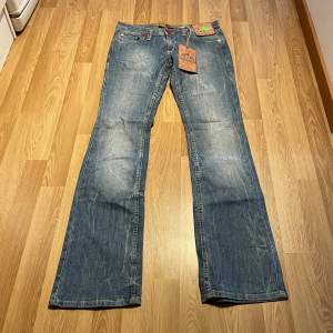 (18) Ljusblå lågmidjade bootcut jeans helt nya med lappar kvar, färgade sömmar. Midjemått rakt över: 39 cm, Innerbenslängd: 86 cm 🩵