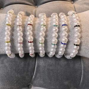 Handgjorda pärlarmband med vita pärlor. Dom glittriga mellanplattorna finns i flera färger som man kan välja själv. Man kan även få armbanden anpassade efter sin storlek med silvrigt spänne eller med gummitråd!💜 40 kr/st.