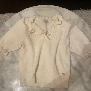 Stickad kortärmad tröja m. pärlor. - Urgullig stickad topp med pärlknappar - jättefin både uppknäppt och knäppt beroende på vad man känner sig för. Använt ett fåtal gånger, nyskick. 🤍