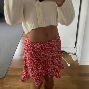 Röd kjol med vita blommor på - En söt sommar/vår kjol med fina detaljer på. Original pris: 200kr 