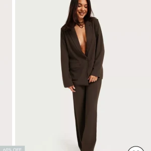 Kostymset brunt  - Brunt kostymset från Nelly helt oanvänt!  Storlek 36 på kavajen och 32 på byxorna 