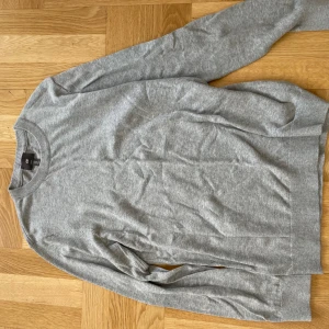 Grå tröja från H&M - Säljer en stilren och bekväm grå tröja från H&M i storlek M. Tröjan har en slim fit passform och är perfekt för både vardag och lite mer uppklädda tillfällen. Den är långärmad och gjord i ett mjukt material som känns skönt mot huden. Perfekt för höst och vinter!