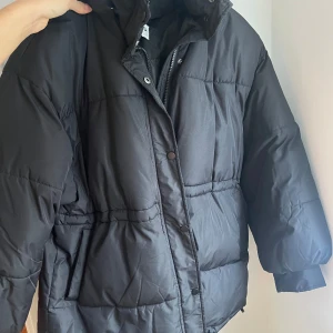 Puffjacka i svart  - Går strax över midjan, bra kvalite och varm. 