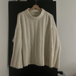 Vit stickad tröja från H&M - Mysig och stilren vit stickad tröja från Gina tricot. Perfekt för kyliga dagar med sin ribbade design och långa ärmar. Tröjan har en avslappnad passform som gör den både bekväm och trendig. Ett måste i garderoben för höst och vinter!