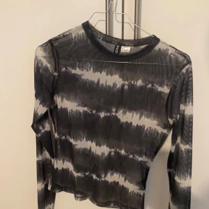 Svart och grå långärmad topp från Divided - Säljer en cool svart och grå långärmad topp från Divided. Den har ett unikt mönster som ger en trendig look. Perfekt för både vardag och fest! 🖤den är genomskinligt 
