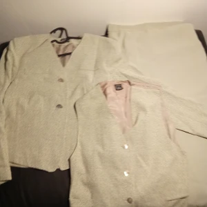 Klassisk 3 delar set från Kello - Danska Kello of Scandinavia 3 delars klassisk kostym set. Kavaj , Vest och kjol Överdelen är storlek 38/ M Kjolen är 36/SMaterial Acetat  Färg  Grå, Grön mönster med ljus rosa underkjol Nyskick 