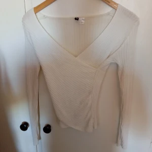 Vit ribbad tröja från H&M - Säljer en superfin vit ribbad tröja från H&M. Den har en snygg omlott-design med v-ringning och långa ärmar. Perfekt för både vardag och fest! Tröjan är i storlek XS och sitter riktigt bra på kroppen.