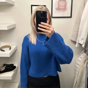 Blå ribbad stickad tröja - Säljer en superfin blå stickad tröja med ribbad struktur. Den är croppad och har långa ärmar.