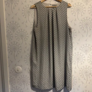 Mönstrad ärmlös klänning - Säljer en stilren ärmlös klänning med ett diskret mönster. Klänningen har en rak passform. Perfekt för en elegant och avslappnad look.