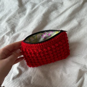 Virkad necessär - Egentillverkad virkad necessär i ett rött garn med innertyg och dragkedja. Höjd ca 12 cm längd ca 16 cm