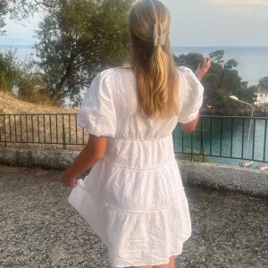 Vit kortklänning med puffärmar och fina detaljer - Charmig vit kortklänning med puffiga kortärmar och v-ringning. Klänningen har en luftig passform och volangdetaljer som ger en romantisk känsla. Perfekt för sommarn!! storlek XS ag brukar personligen ha M men den är stor i storleken. Skicka privat för fler bilder!! nypris 700💋💋💋💋