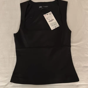 Svart ärmlös topp från Zara - Snygg svart ärmlös topp från Zara. Toppen har en perfekt passform och helt nyköpt, aldrig använd.