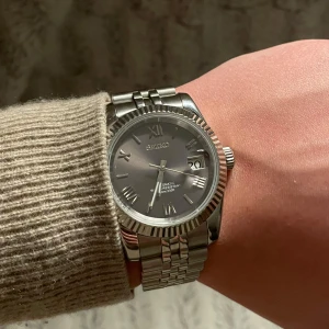 Datejust Seiko Mod - Extremt elegant silverfärgad klocka från Seiko med automatisk urverk och datumvisning. Som efterliknar modellen ”Datejust”Klockan har en stilren design med romerska siffror och en robust länkarmband i metall. Perfekt för den som söker en tidlös accessoar. Alla länkar tillkommer vid köp! 39mm. Klockan är automatisk med en NH34 movement. Om det är några frågor är det bara att ställa dem privat!