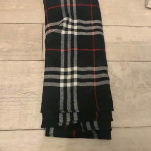 Burbery scarf i jätte bra kondition och äldrig använd - Burbery scarf i jätte bra kondition med jätte fin mönster i vitt och rött. Perfekt för att hålla sig varm under kyliga dagar. Den har en stilren design som passar till många olika outfits.