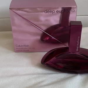 Deep Euphoria parfym från Calvin Klein - Säljer en elegant Deep Euphoria parfym från Calvin Klein. Flaskan har en unik, modern design i en djup lila färg och rymmer 100 ml. Perfekt för den som vill ha en sofistikerad doftupplevelse. Endast testad