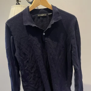 Mörkblå pikétröja från Jack & Jones - Säljer en stilren mörkblå pikétröja från Jack & Jones. Tröjan har långa ärmar och en klassisk krage med knappar. Perfekt för en avslappnad men ändå uppklädd look.