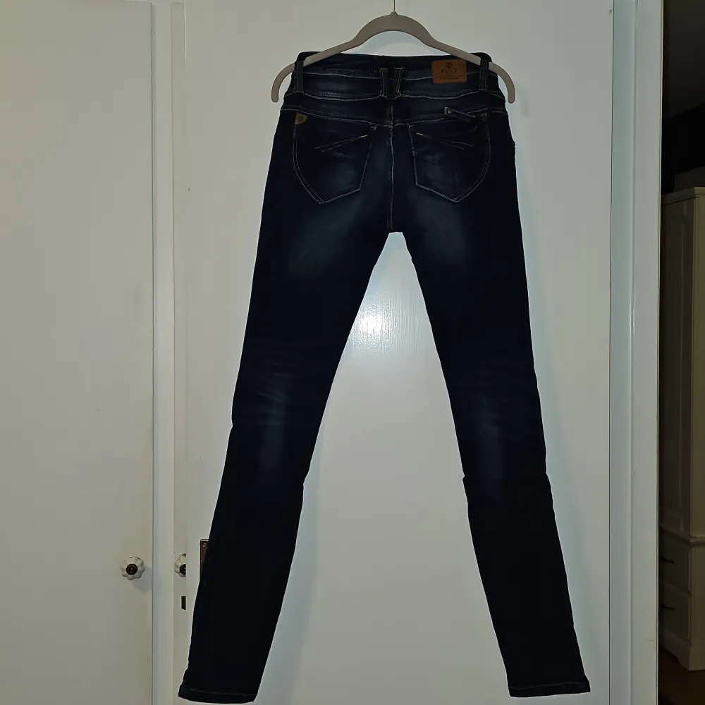 Snygga mörkblå skinny jeans från Pulz i en stretchig bomullsblandning. De har en midwaist passform och klassisk femficksdesign. Perfekta för en stilren look.. Farkut & Housut.